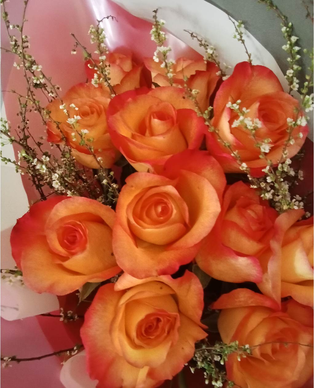 Fiery Elegance bouquet with vibrant orange and red roses, accented by white baby's breath. Perfect Phuket flowers for passionate occasions.