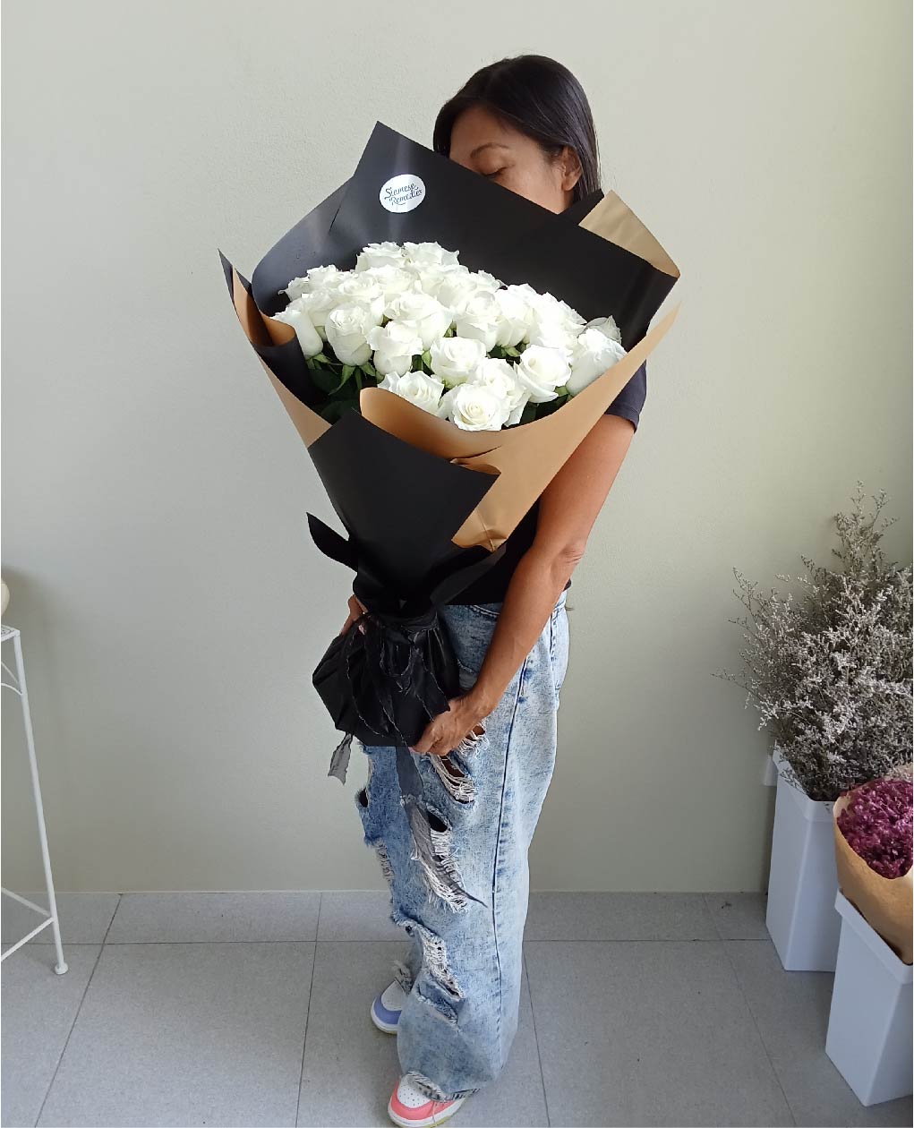 Elegant 'Midnight Desire' bouquet of white Phuket roses wrapped in black and tan paper, perfect for romantic gestures.