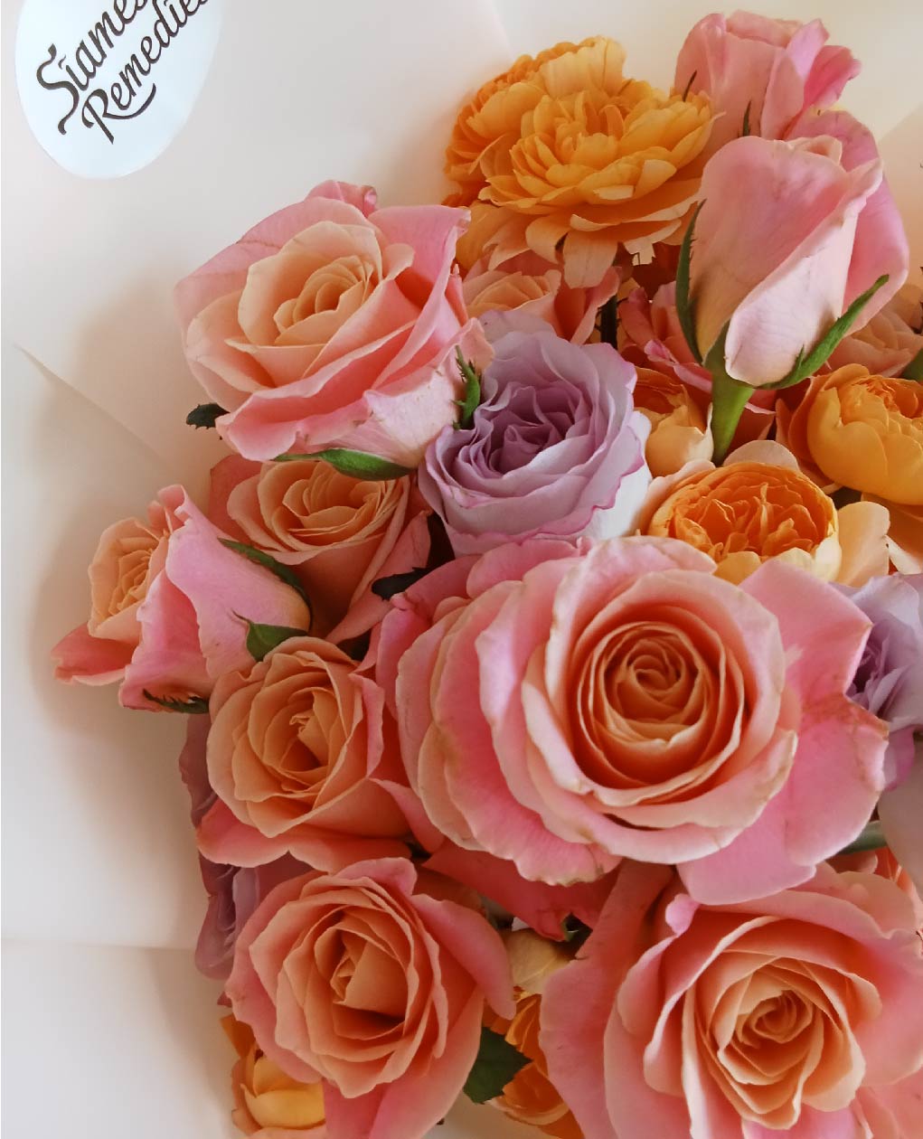 Elegant peach and pink roses with purple accents in a romantic Phuket flower bouquet featuring lush carnations.